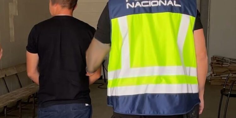 Un agente de policía traslada a uno de los detenidos. / PN