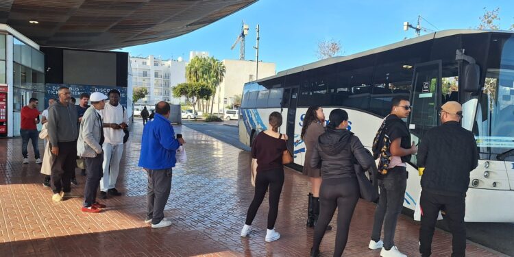 Usuarios del transporte público, en su gran mayoría migrantes, hace cola frente un autobús en la estación de Sant Antoni durante la mañana de ayer. / D.V.
