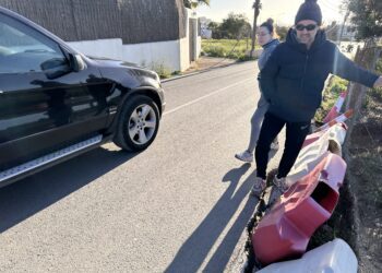 Un coche esquiva a dos peatones que caminan por el acceso a Cas Mut junto a los socavones que se han cubierto parcialmente con bloques y conos.