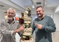 El artista Gerry Clark y su hijo, el poeta Ben Clark, junto a una obra de Gerry, de 1991, que representa el pastel de bodas de su enlace con Elaine Clark. Foto Noudiari.es