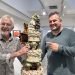 El artista Gerry Clark y su hijo, el poeta Ben Clark, junto a una obra de Gerry, de 1991, que representa el pastel de bodas de su enlace con Elaine Clark. Foto Noudiari.es