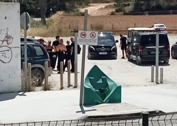 Aparcamiento del CEIP L'Urgell con varias personas dejando sus vehículos y furgonetas negras. Foto de Noudiari.es