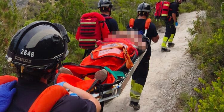 Los bomberos portean a la mujer rescatada en el camino a Es Portitxol.