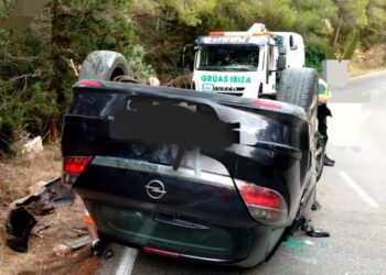 El vehículo volcado mientras estaba siendo retirado por una grúa pluma de Grúas Ibiza.